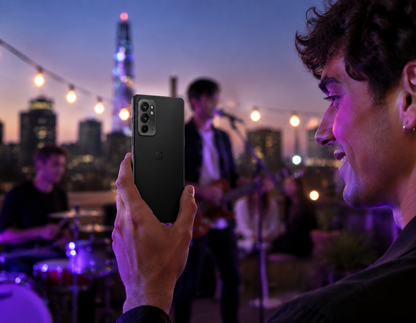 Person holding a black OnePlus 9RT 5G smartphone in low light